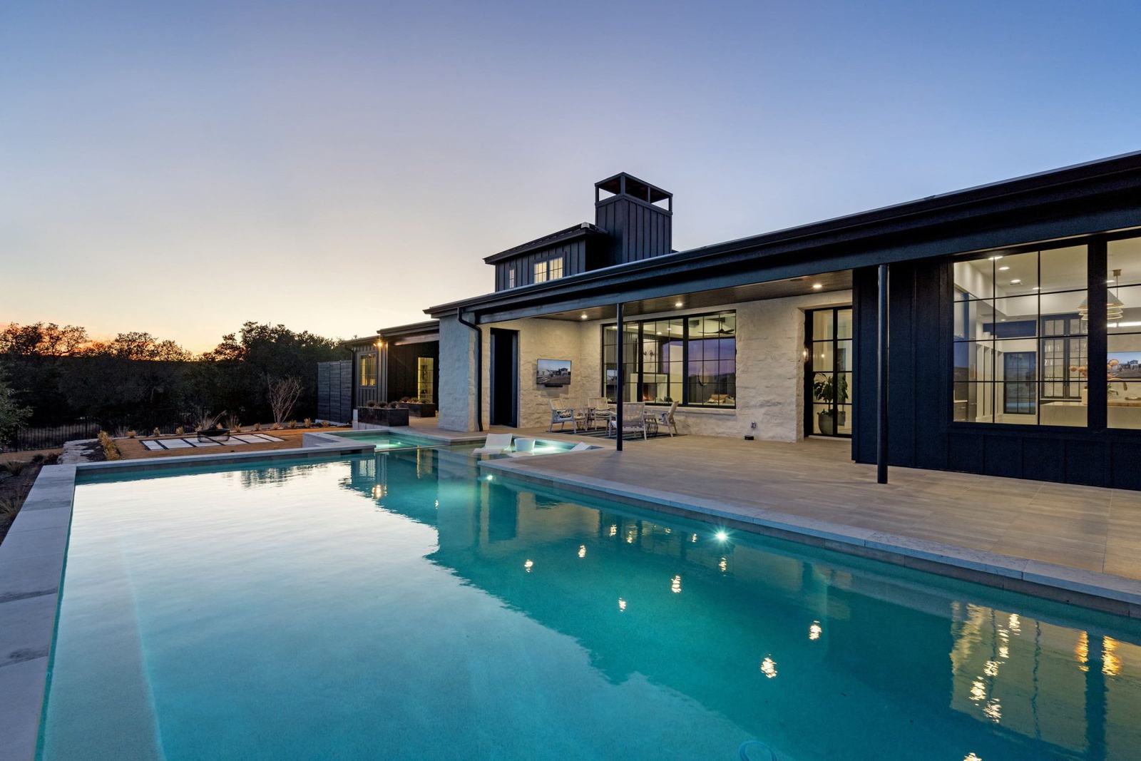 Contemporary home and pool at blue hour, interior lights on
