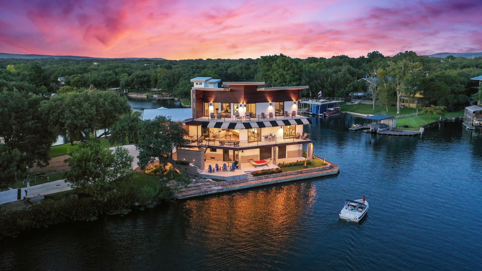Lakefront home at dusk photographed from the air with the water glowing